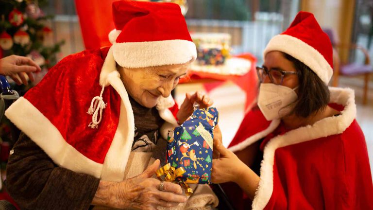 Anziana con cappello natalizio riceve pacco regalo