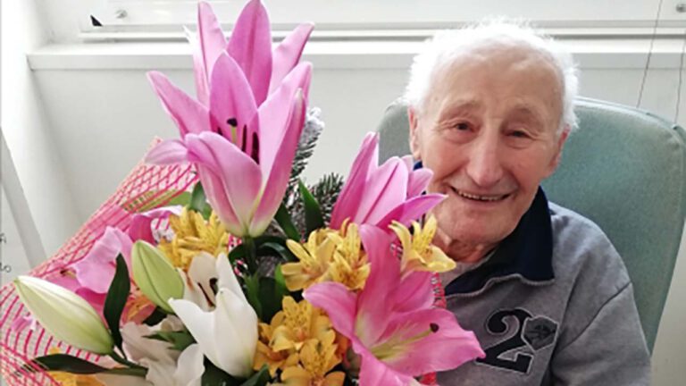 Anziano sorride con mazzo di fiori